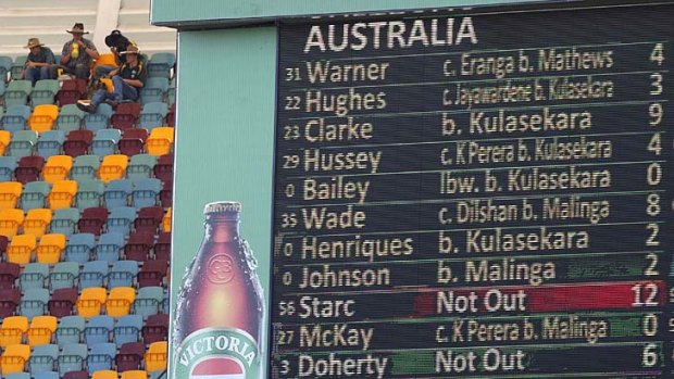 Not a pretty sight: fans sit next to a scoreboard displaying the Australian team's score.