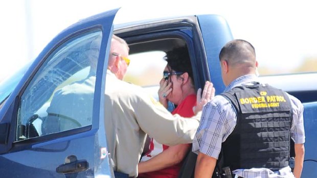Five dead ... a Yuma County Sheriff's deputy and a Boarder Patrol agent speak to a distressed woman outside of residence east of Wellton, Arizona.