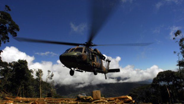 An army helicopter makes a tight landing near the crash site.