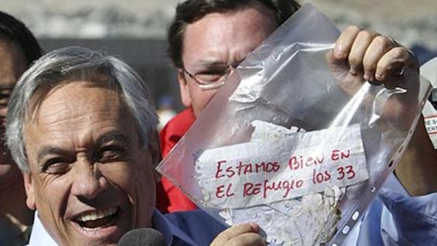 Chile's President Sebastian Pinera holds up a plastic bag containing a message from the trapped miners that reads in Spanish "We are ok in the refuge, the 33 miners"