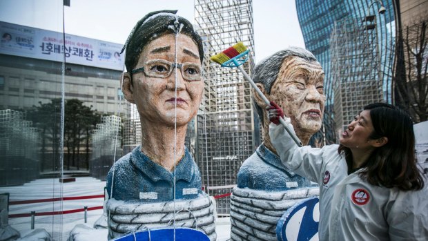 A protester sweeps effigies of Jay Y. Lee, left, and Chung Mong-koo, chairman of Hyundai Motor Co., outside Samsung's Seocho office building in Seoul, South Korea.
