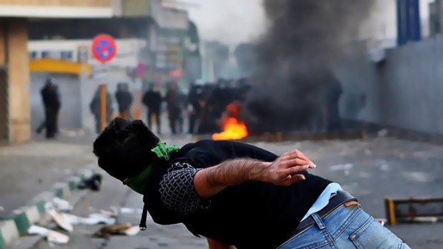A protester throws a projectile at riot police in Tehran.