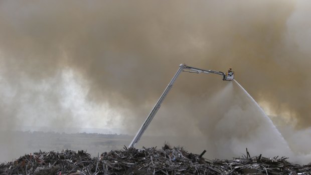 CFA workers high above the massive pile of wood. 