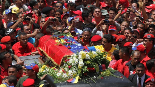 Venezuela's Vice President Nicolas Maduro, wearing a yellow jacket, walks alongside the flag-draped coffin carrying the remains of Hugo Chavez  as it is paraded through Caracas on Wednesday.