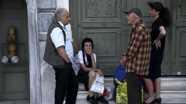 Pensioners wait outside a National Bank branch to receive part of their pension in Athens on Wednesday.