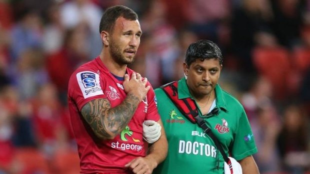 Setback: Reds five-eighth Quade Cooper leaves the field with an injured shoulder during Saturday night's match against the Rebels.