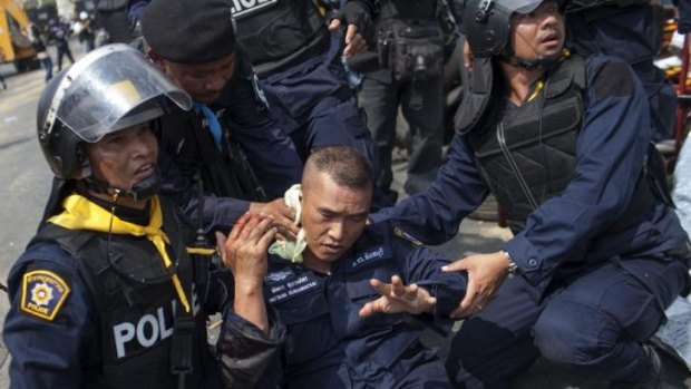 Police treat an officer injured by a grenade thrown by anti-government protesters in Bangkok.