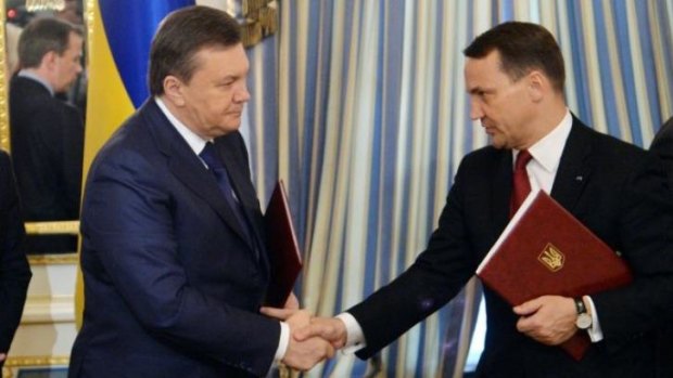 Former Ukrainian president Viktor Yanukovych (L) and Polish Foreign Affairs Minister Radoslaw Sikorski shake hands on a peace deal for Ukraine.