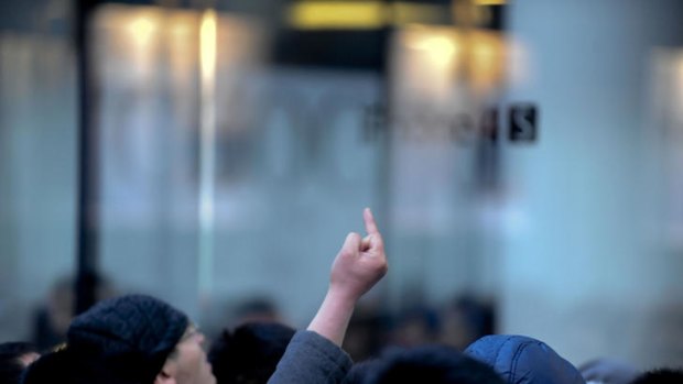A Chinese man gestures as thousands of customers queue up outside an Apple store in Beijing.
