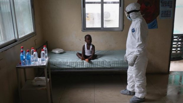 LONELY WAIT: A Liberian health worker dressed in an anti-contamination suit speaks with a boy at a centre for suspected Ebola patients.
