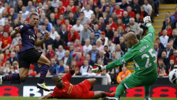 Arsenal's Lukas Podolski shoots past Liverpool's Pepe Reina.