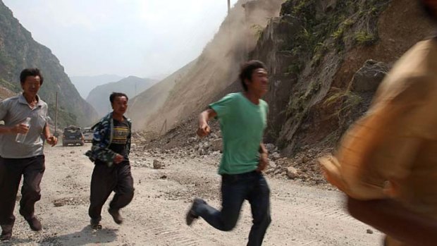 Danger ... men run to avoid falling rocks during an aftershock.