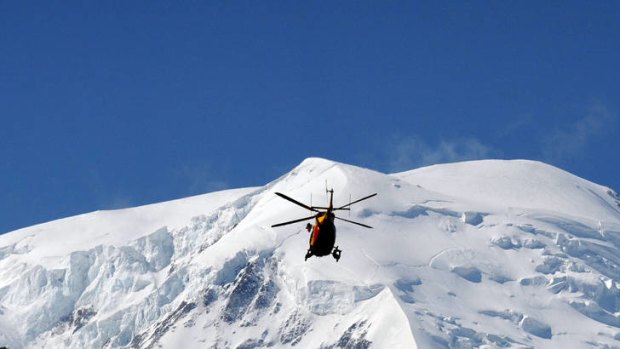 A French rescue helicopter flies over the Mont Blanc massif searching for avalanche survivors.