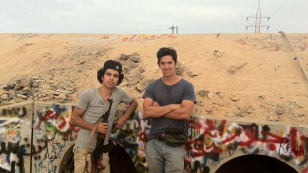 Adventurer ... student Tom Lee with a Libyan rebel fighter at the site where Gaddafi was dragged from a drain in Sirte.