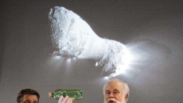 Project manager Tim Larson, left, watches as Michael A'Hearn, principal investigator, uses a plastic bottle to describe the rotation of the Comet Hartley 2, beneath an image of the comet made from the NASA EPOXI Deep Impact spacecraft.