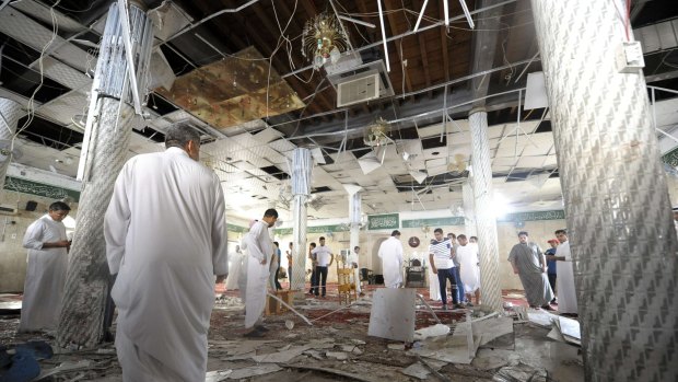 Saudi men gather around debris following a blast inside a mosque, following the suicide bombing of a Shiite mosque in al-Qadeeh.