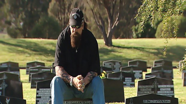 Geoff "Snake" Campbell, a former member of the Bandidos bikie gang, sits on the grave stone of one of his brothers - two of which died at Milperra in the Father's Day massacre.