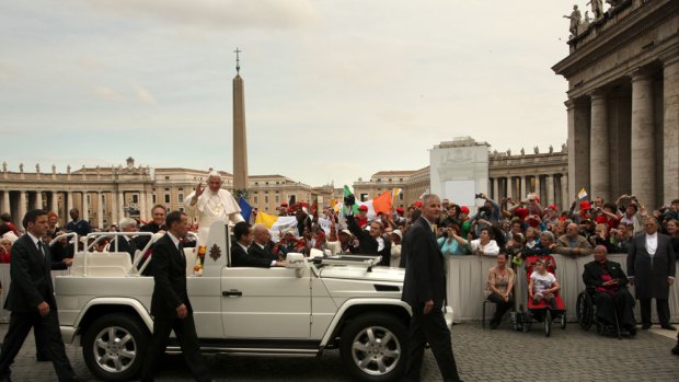 The Pope greets the crowd from his Popemobile yesterday,  watched by Sophie Delezio and her mother, Carolyn Martin, seated right.