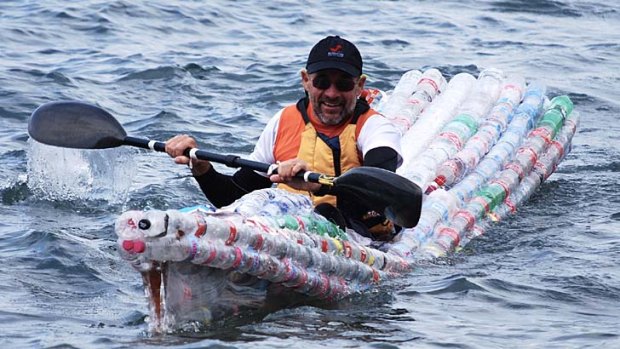 Tom Simmat paddles on the harbour in a boat made of plastic bottles.