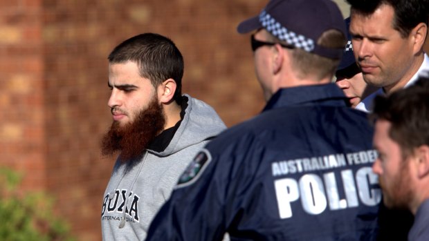 A man is led away by police in Seabrook as simultaneous raids are carried out across Melbourne on Tuesday morning. 