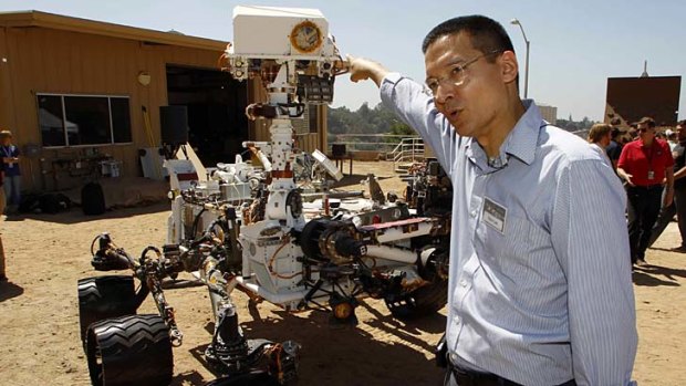 Guidance, Navigation, and Control Systems Manager and Deputy Surface Phase Lead Steve Lee points to the remote sensing mast which includes navigation cameras and a ChemCam laser on an engineering model of NASA's Curiosity Mars rover