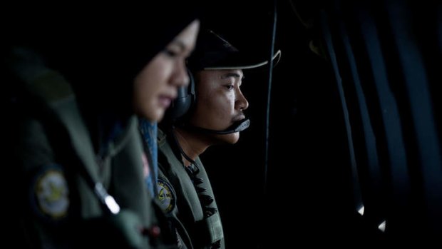 Crew members looking outside windows from a Malaysian Air Force CN235 aircraft working during a search and rescue operation to find the missing Malaysia Airlines flight MH370 plane over the Strait of Malacca.