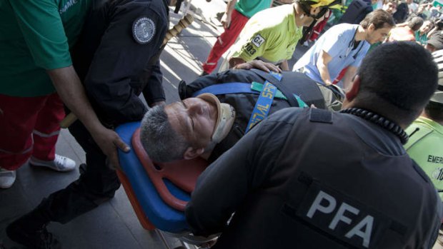 Police and paramedics carry a wounded passenger to an ambulance after a commuter train slammed into the end of the line at a station in Buenos Aires.