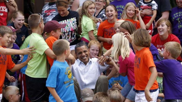 Schoolchildren in Minnesota help President Barack Obama up after posing for a photo during his bus trip of the midwest.