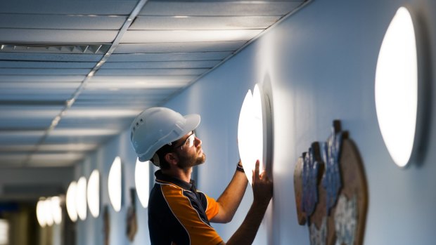 Canberra Hospital mechanical supervisor Sam Bryant fitting some of the new LED light bulbs throughout the hospital. 