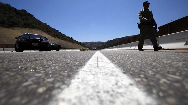 A police officer walks across the empty stretch of the Interstate 405 freeway in Los Angeles.