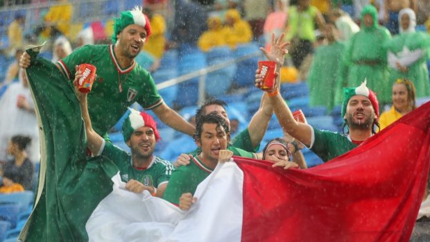 Mexico fans wave a flag as the rain pours down during the match between Mexico and Cameroon at Estadio das Dunas in Natal, Brazil. 