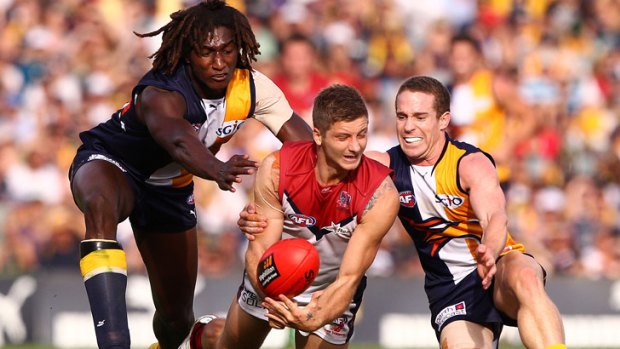 Surrounded: Melbourne's Ricky Petterd tries to handball as he’s tackled by Eagles Nic Naitanui (left) and Ashton Hams yesterday.