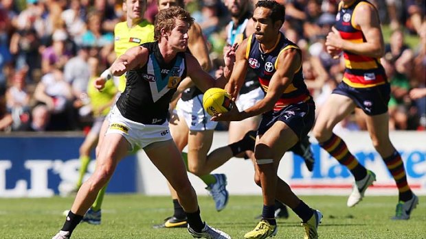 Crows recruit Eddie Betts gets ready to pass the ball as Port's Matt White approaches.