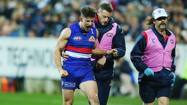 Tom Liberatore is helped from the ground after injuring his ankle against Geelong.