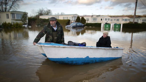 Ian Peacock pulls a boat carrying fellow resident Caroline Hine as they rescue possesions from flooded caravans at the Little Venice Country Park in Yalding, England.