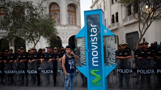 Police stand guard as a man makes a phone call during a protest in Lima calling for justice in the Odebrecht corruption scandal.