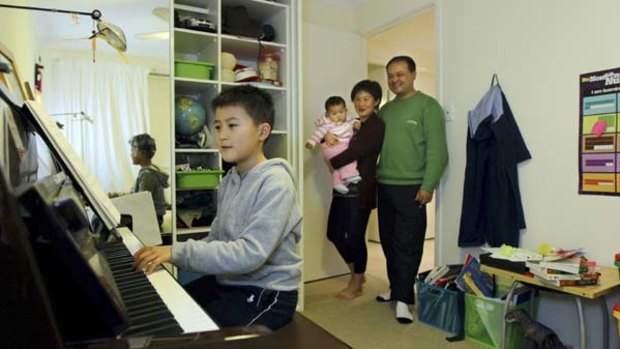 Key performer ... Dawei Yuan, 8, practises piano as his mother and father, Jean and Tim (with eight-month-old Sydney), listen in.