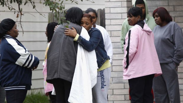 Family and friends console each other outside the house in Houston where two people were shot dead at an 18th birthday party.