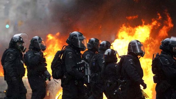 Riot police walk by a burning police car in downtown Toronto during anti G20 protests.