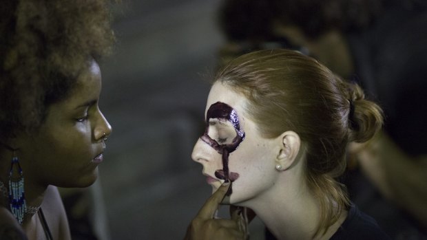 Women paint their faces with female gender symbols for a protest against the gang rape of a 16-year-old girl in Rio de Janeiro.