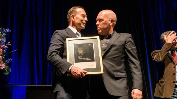Tony Abbott hands Richard Flanagan the Prime Minister's Literary Award for fiction.
