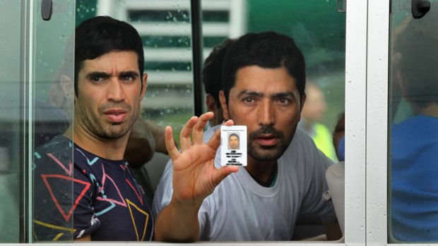Plea for help: Behrad holds up his identity card for the media to see before being driven away to detention on Manus Island while his wife waits in Brisbane.