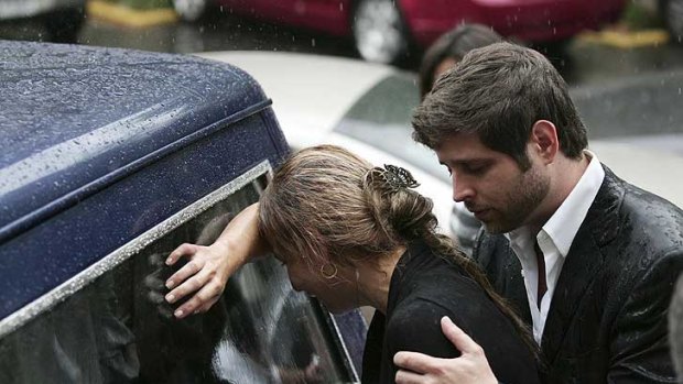 Relatives of Karen Berendique cry over the hearse carrying her coffin.