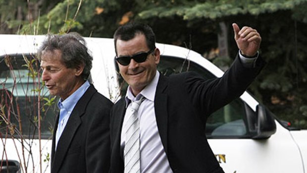 Charlie Sheen waves as he leaves court in Aspen.
