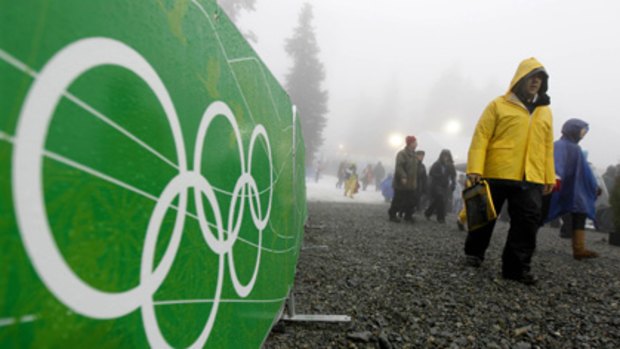 Fans try to stay dry in the rain and fog as they arrive for the women's snowboard cross event.
