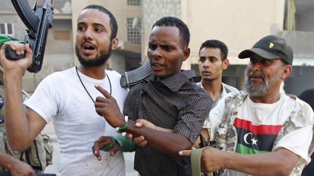 Captured ... Libyan rebel fighters detain an alleged mercenary.