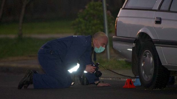 A forensic officer records the discovery of a shell casing.