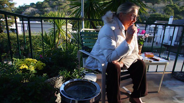 Outraged and outdoors: Edith Frederickson smokes in a designated area near her flat.