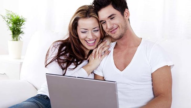 UNWIND 9 July 2013. Happy young couple working on laptop - Smiling young couple sitting on white sofa working on laptop computer. iStock Photo File #15410343