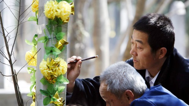 Chinese men repaint the inscription on a Muslim grave at the annual Qingming or tomb-sweeping festival.